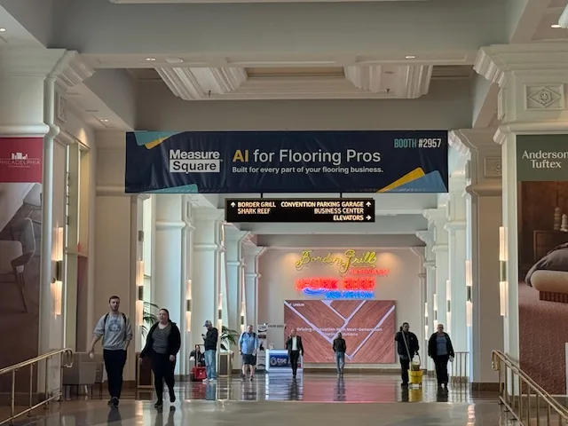 MeasureSquare 'AI for Flooring Pros' hanging banner over a convention hallway